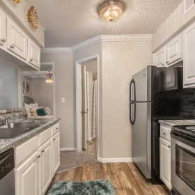 Spacious kitchens with thoughtful details a kitchen with white cabinets a sink a stovetop a dishwasher and a fridge