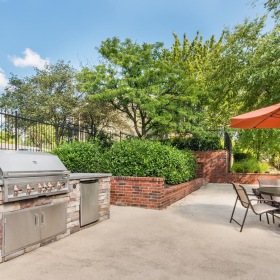 Settle into comfort at Highland Ridge a patio with a table and chairs and a grill and an umbrella