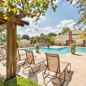 Relax and unwind poolside a pool with lounge chairs and tables next to it